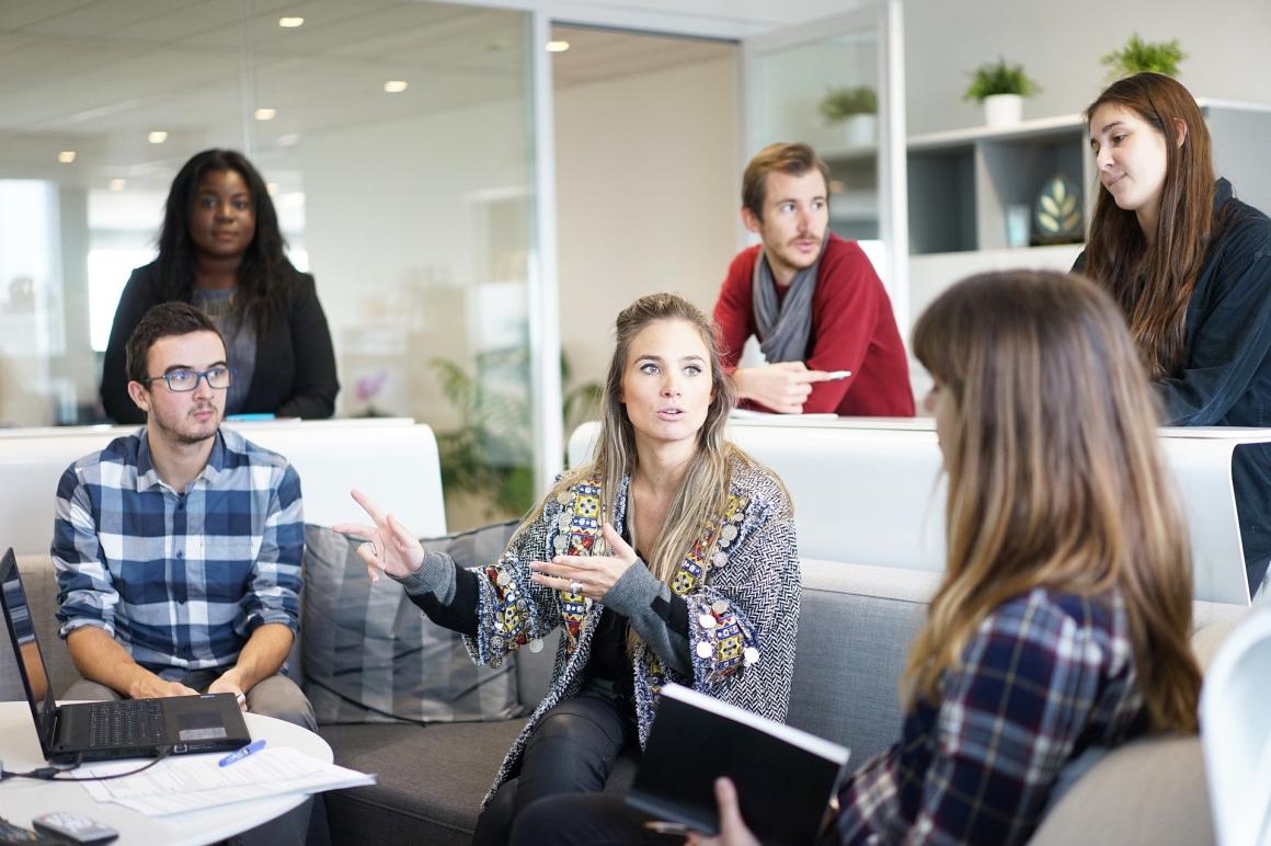 Personen in einem Büro im Gespräch miteinander von Laptops