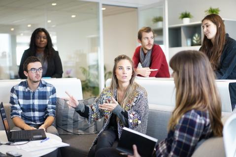 Personen in einem Büro im Gespräch miteinander von Laptops